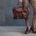 a person is carrying a men’s leather bag