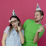 A man and a woman using a party prop to celebrate a party